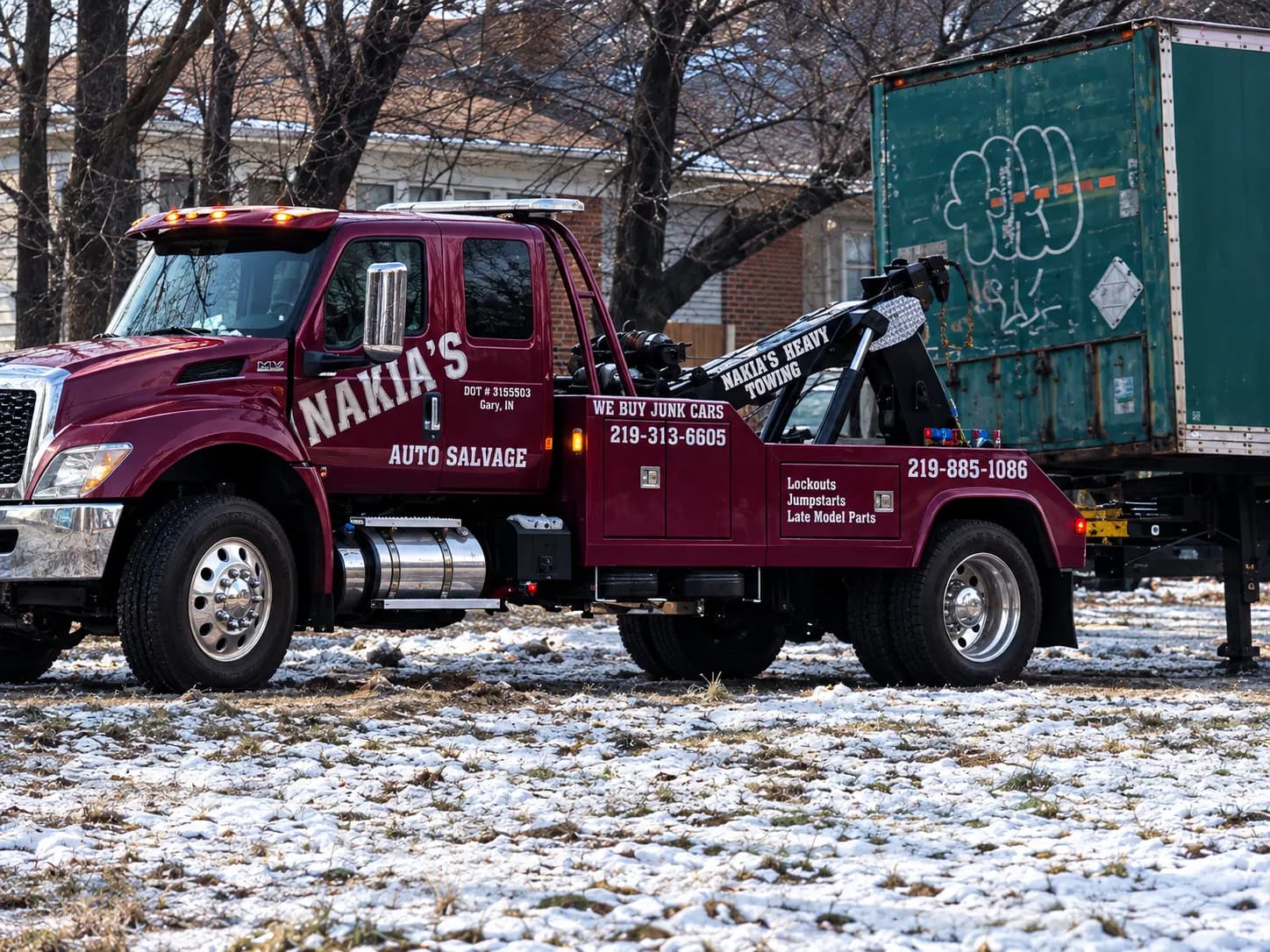 Nakia's Heavy Towing wrecker parked beside a box trailer